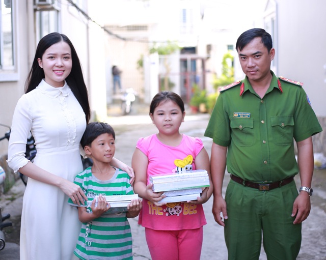 Hoa khôi cùng chiến sĩ công an khu vực mang sách, vở đến trao tặng các em nhỏ trong năm học mới.