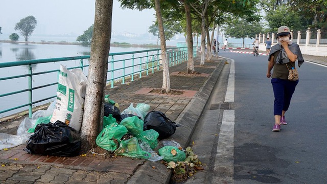 Hồ Tây từ xa xưa đã là thắng cảnh nổi tiếng đất Hà Thành với không gian mặt nước rộng hơn 500ha, được ví như lá phổi của Thủ đô. Nhưng những đống rác hôi thối được người dân xả bừa bãi bên con đường ven hồ làm xấu cảnh quan, gây ô nhiễm. Trong ảnh là một phụ nữ đi tập thể dục buổi sáng phải bịt mũi khi đi qua một đống rác trên phố Quảng Khánh