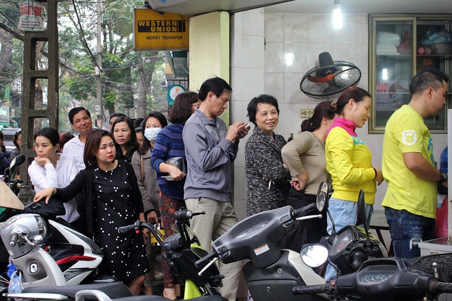 Năm nay lượng người mua bánh đông nên khách hàng phải chờ khá lâu mới đến lượt. Nhiều người tranh thủ thời gian chờ đợi sử dụng điện thoại để giết thời gian.