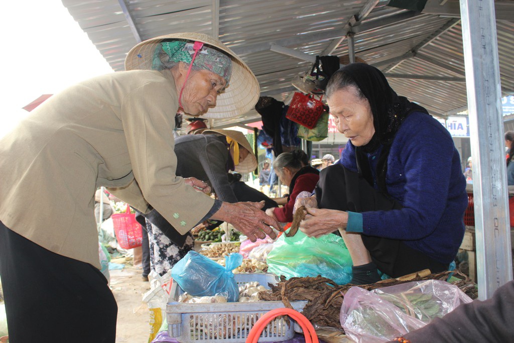 Hai bà cụ đang trao đổi với nhau hàng thuốc lá, một loại cây dùng để hút được trồng ở nông thôn