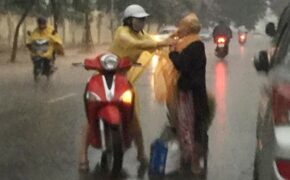 Cảm động hình ảnh cô gái dừng xe, mặc áo mưa cho bà cụ không quen
